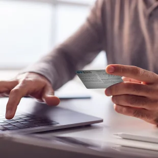 BCBS member using a laptop and ID card to find plan